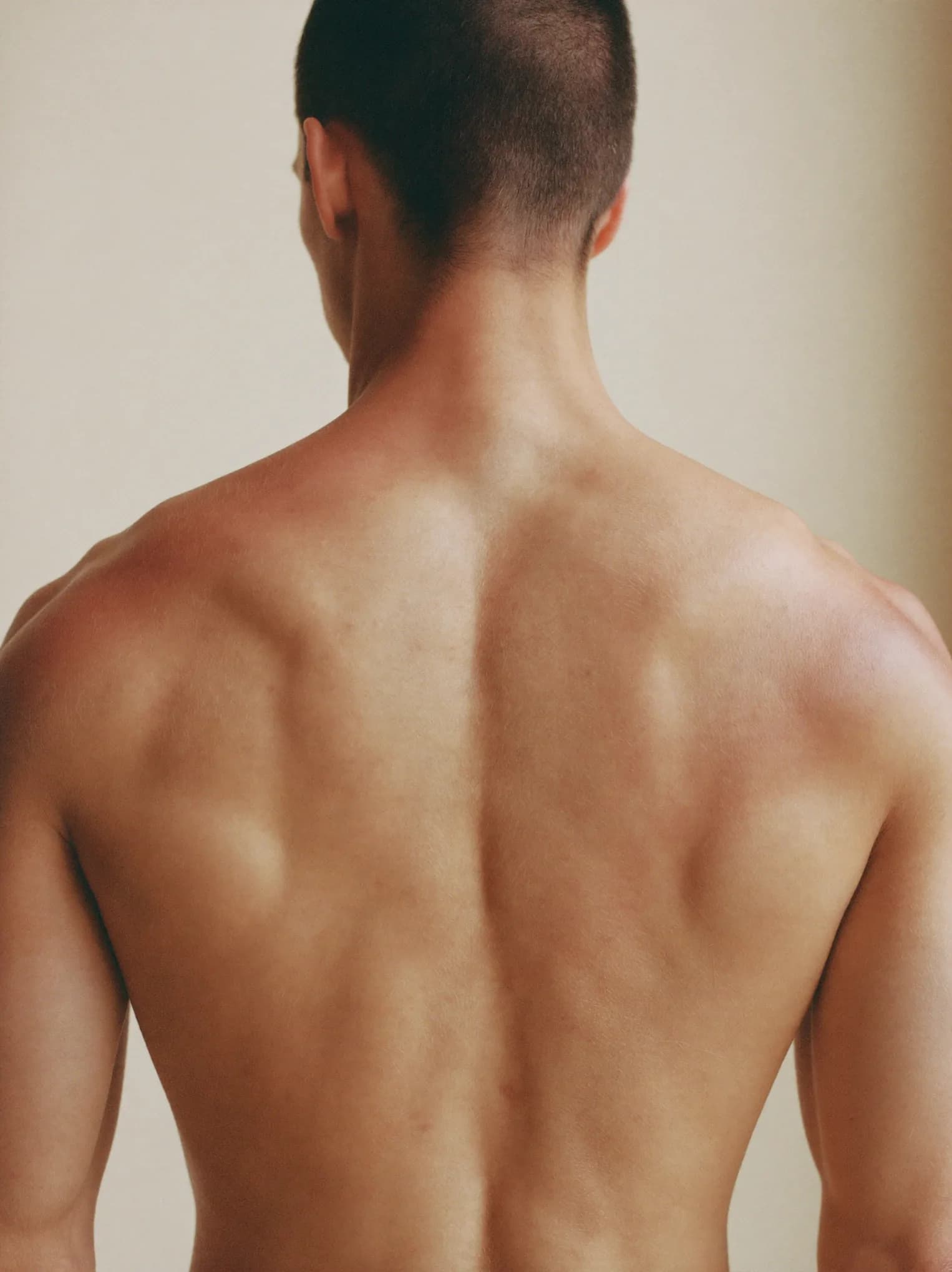 Espalda y hombros de hombre con piel lisa, luz suave lateral